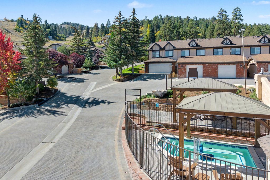 Hot tub area with mountain view and nearby townhomes surrounded by pine trees.
