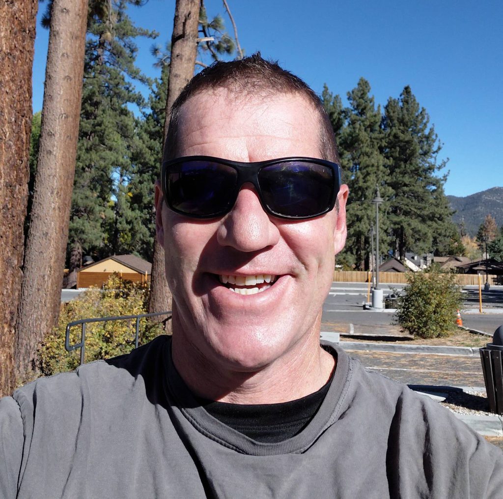 Tom smiling outdoors in casual attire