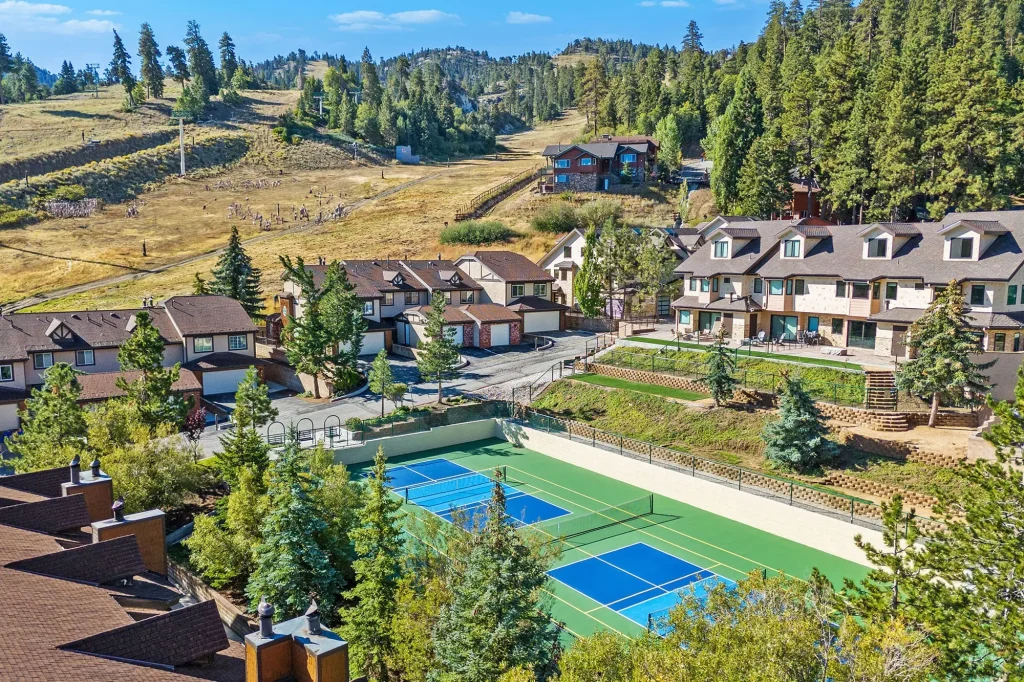 A vibrant pickleball court surrounded by trees and mountain views, perfect for recreational play in a scenic location.