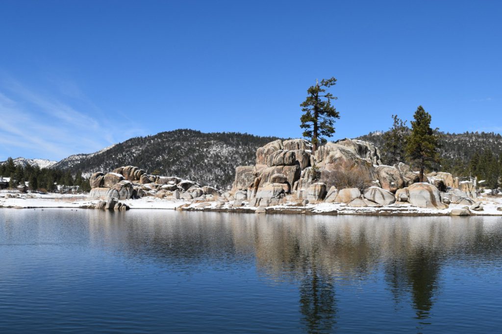 Rocky Big Bear landscape covered in snow beside calm lake waters