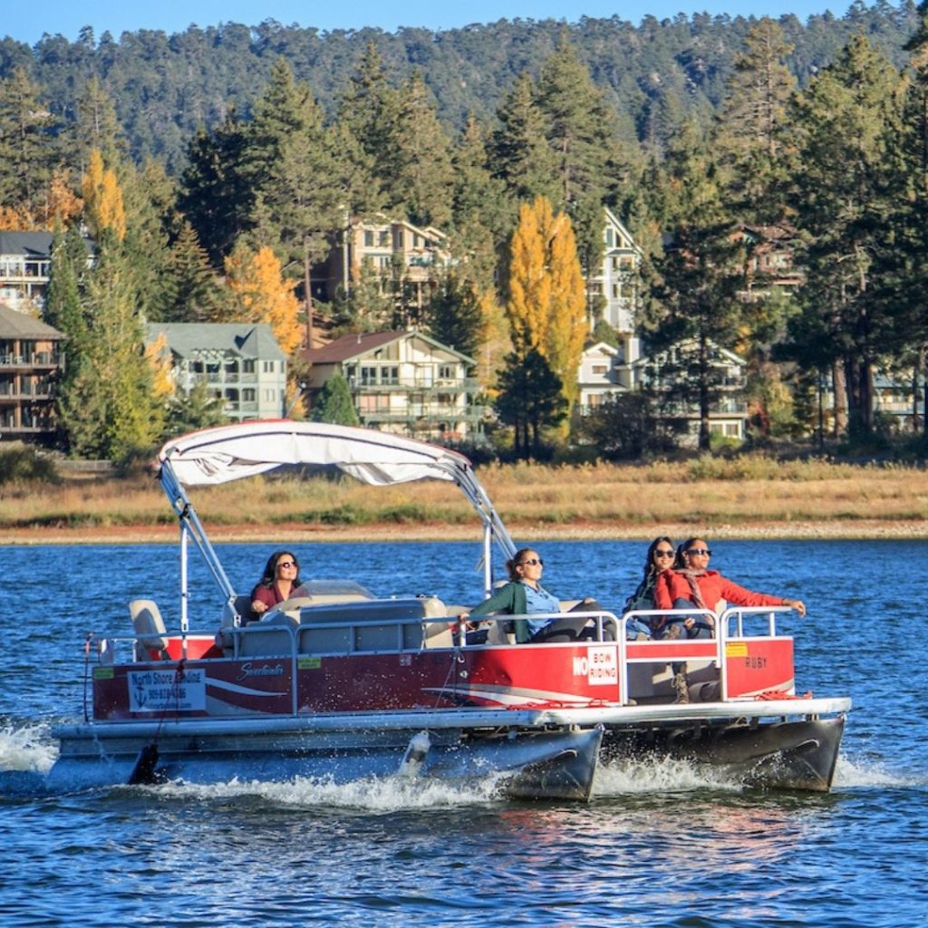 A group of people enjoying a sunny day on a pontoon boat, cruising on a lake.