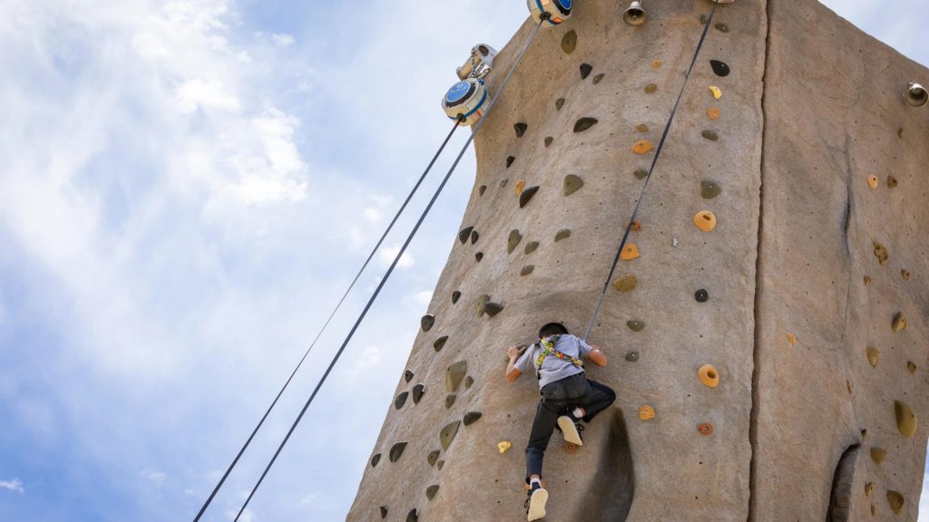 A person climbing a rock wall on an outdoor climbing adventure.