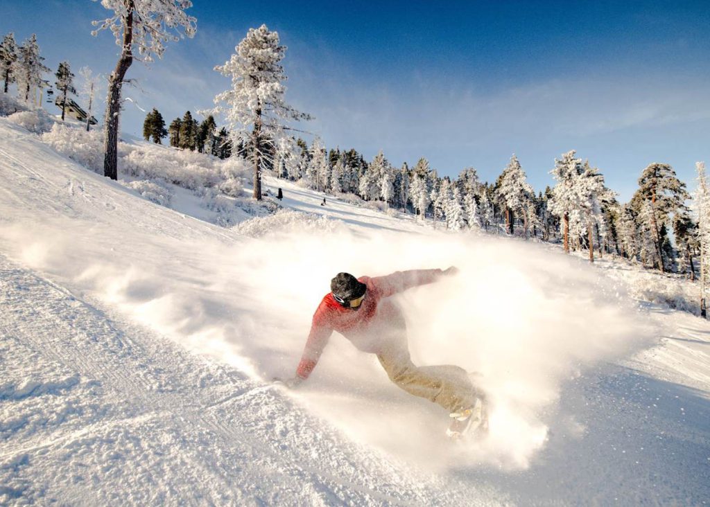 A person snowboarding down a snowy slope with a spray of snow behind them.