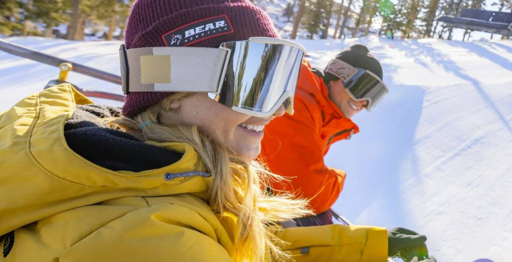 A stunning winter view of Bear Mountain, covered in snow, with ski runs and pine trees in the distance.