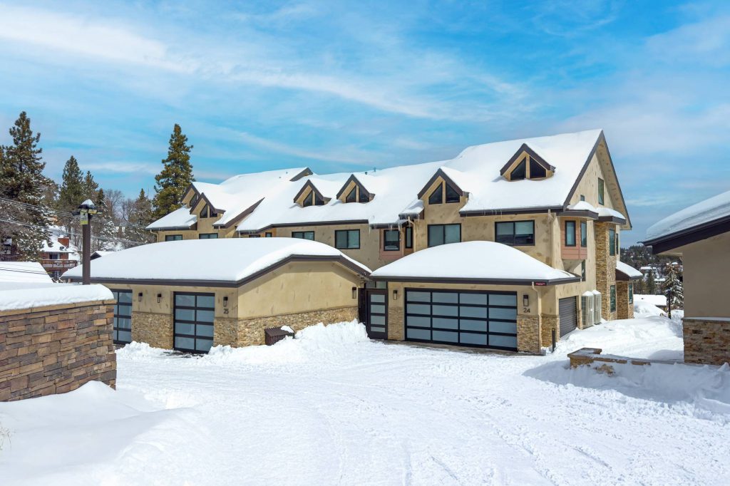 Wide exterior view of Comstock Highlands condos covered in snow with blue sky background