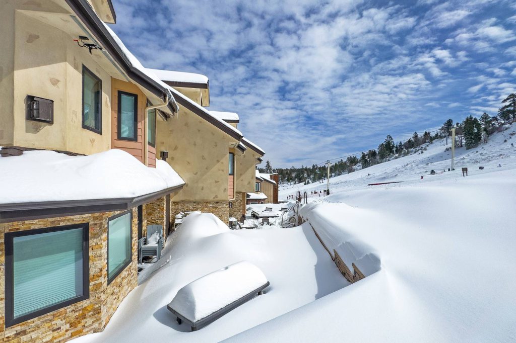 Snow-covered patio area of Comstock Condos with ski slope visible in background