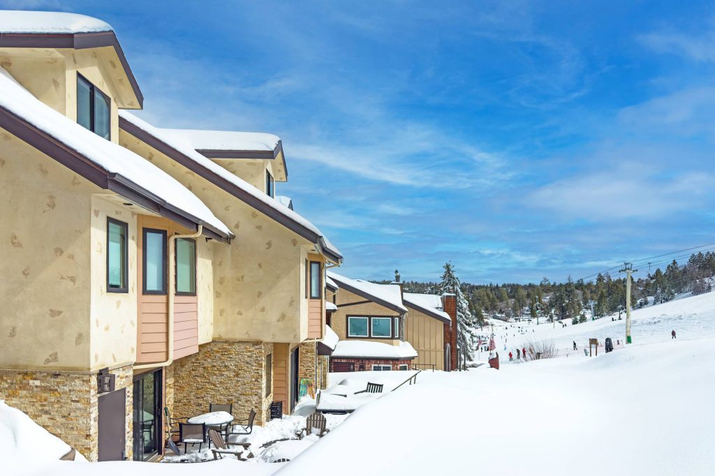 Backside of Comstock Condos with snow-covered deck and ski lift in distance