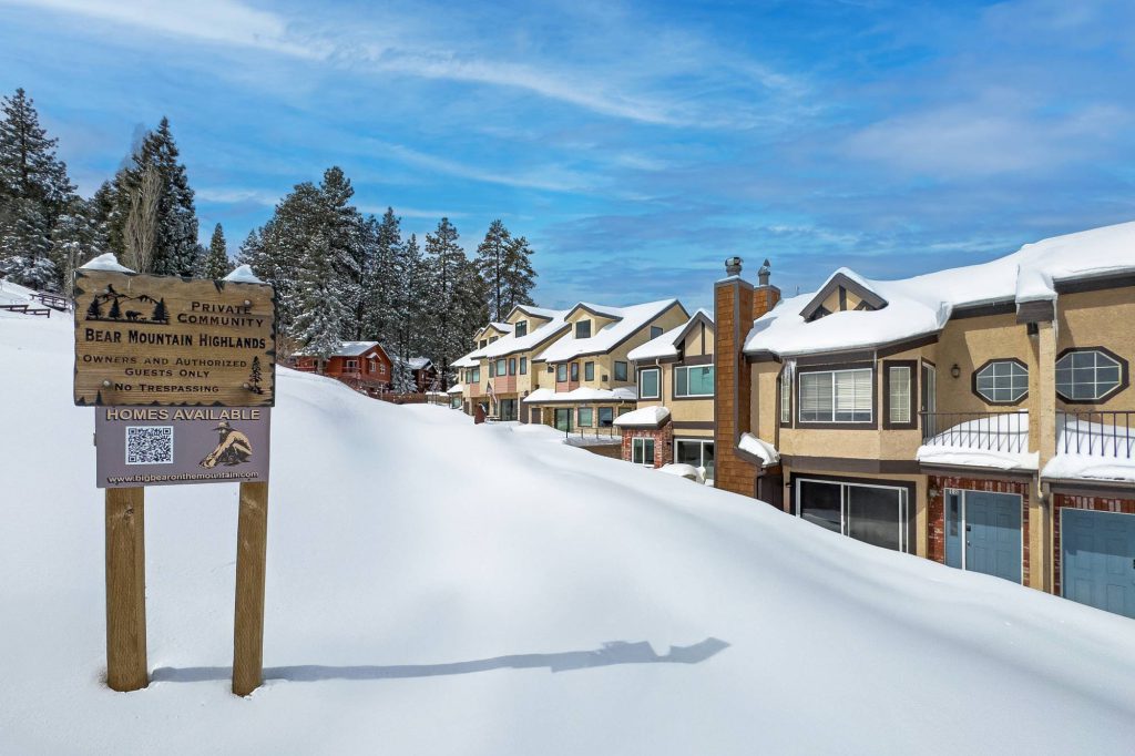 Private Community sign for Bear Mountain Highlands with snow-covered condos in Big Bear Lake