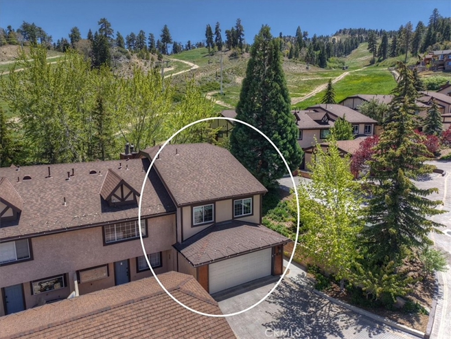 Townhome near mountain slopes with surrounding trees and residential neighborhood aerial view